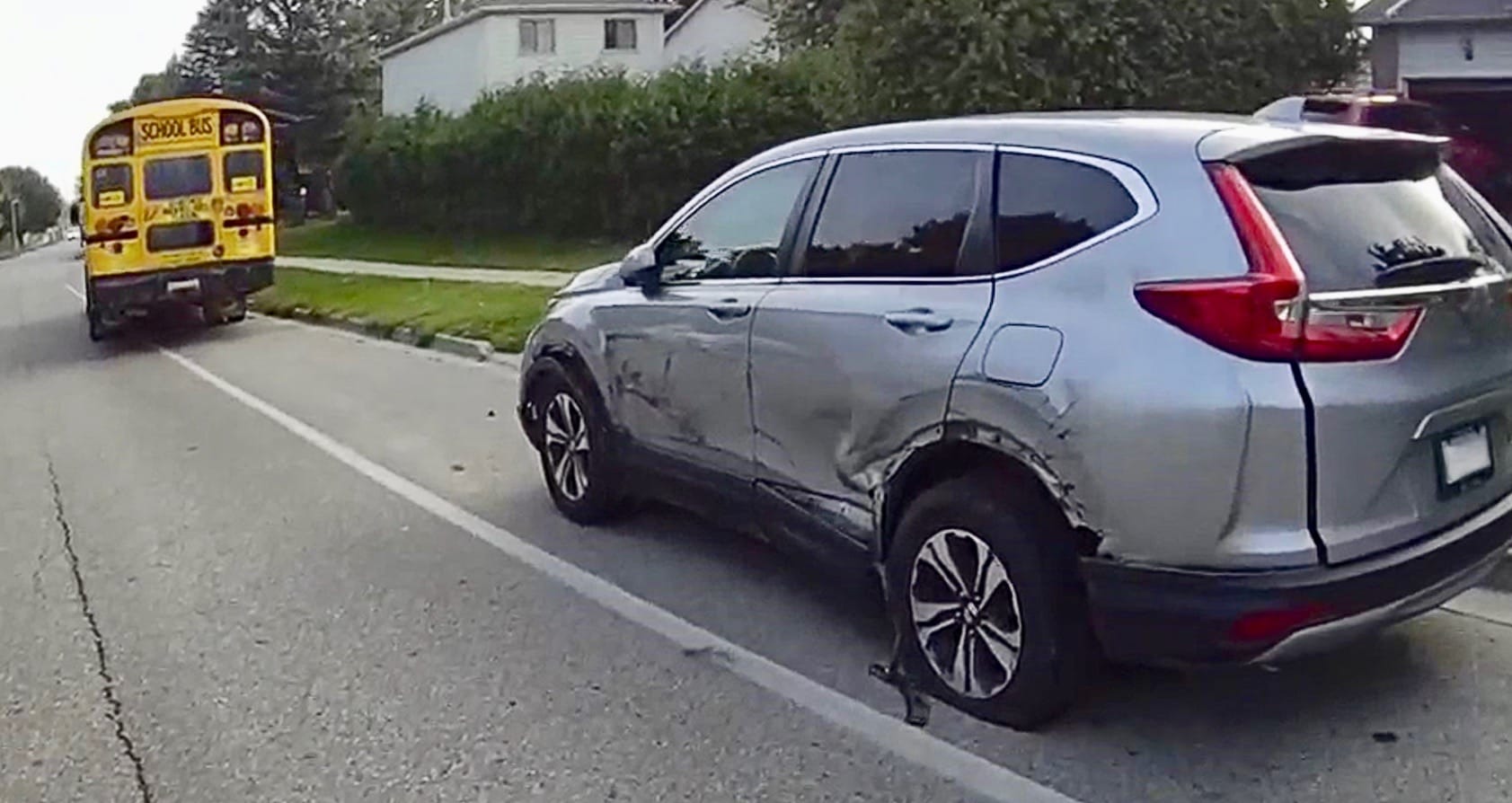 Driver charged after school bus full of students hits parked car